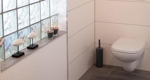 biała łazienka z toaletą i oknem w obiekcie Meisterhaus Apartments w mieście Glauchau