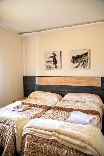 two beds in a room with pictures on the wall at Lagunas de Sanabria in Trefacio