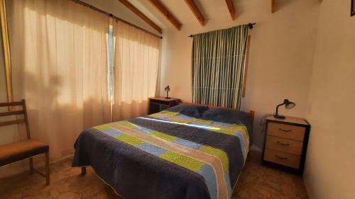 1 dormitorio con 1 cama, 1 silla y 1 ventana en Parcela Paso del León (Cabañas), en Olmué