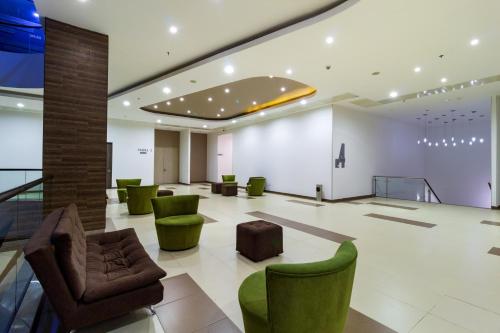 a large lobby with green chairs and tables at Hotel Mocawa Plaza Armenia in Armenia