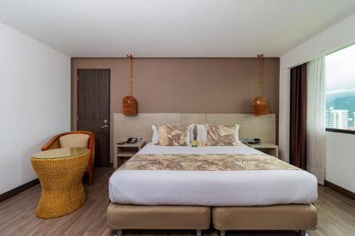 a bedroom with a large bed and a chair at Hotel Mocawa Plaza Armenia in Armenia
