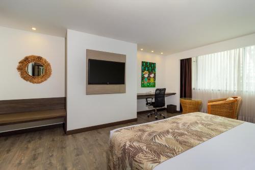 a bedroom with a bed and a desk and a tv at Hotel Mocawa Plaza Armenia in Armenia