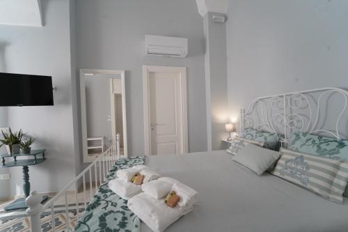 una camera da letto bianca con un letto e asciugamani di B&B Puglia d'aMare a Lizzano
