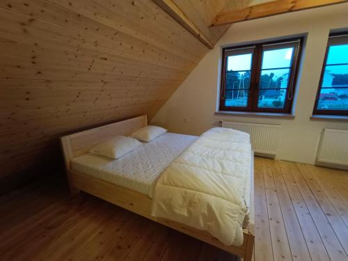 Łóżko w pokoju z drewnianymi podłogami i oknami w obiekcie Domek całoroczny na Kaszubach w mieście Lipusz
