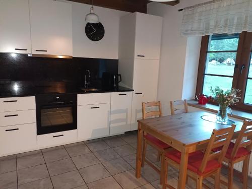 a kitchen with white cabinets and a wooden table at Domek całoroczny na Kaszubach in Lipusz