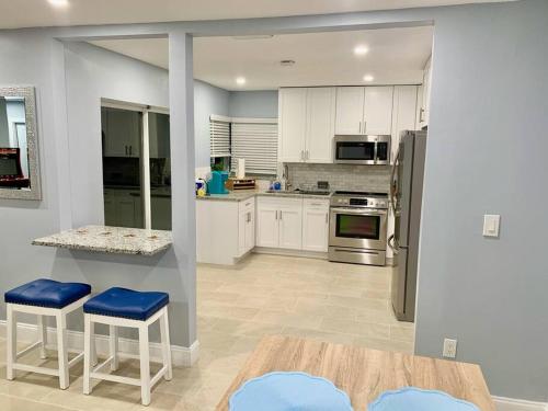 una cocina con armarios blancos y taburetes azules. en Home in West Palm Beach with Heated Pool, en West Palm Beach