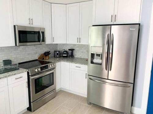 a kitchen with white cabinets and a stainless steel refrigerator at Home in West Palm Beach with Heated Pool in West Palm Beach