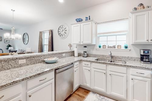 a kitchen with white cabinets and a sink and a window at Cast a Waves in Panama City Beach