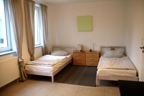 1 Schlafzimmer mit 2 Betten, einer Kommode und Fenstern in der Unterkunft Ferienwohnung Philippstraße 35 in Meerane