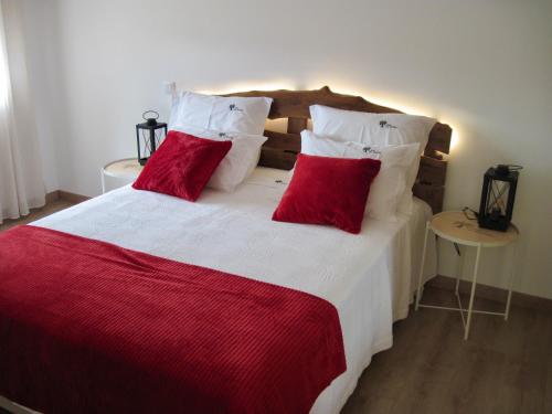 een slaapkamer met een groot bed met 2 rode kussens bij Casas nas Hortas 