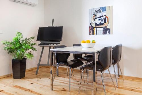 a dining room table with chairs and a television at BO - Almada in Porto