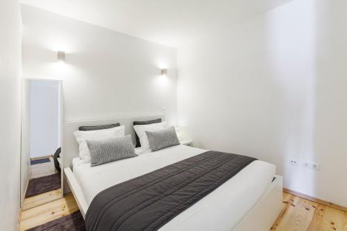a bedroom with a large white bed with gray pillows at BO - Almada in Porto