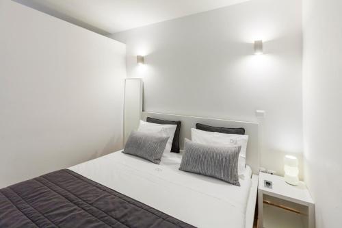 a white bedroom with a bed with two pillows at BO - Almada in Porto