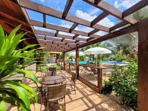 un patio con mesas y sillas bajo una pérgola de madera en Pousada Surucuá - Bonito MS, en Bonito