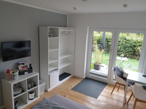 ein Wohnzimmer mit weißen Regalen, einem Tisch und einem Fenster in der Unterkunft Willkommen zu Hause, ankommen & wohlfühlen ! in Tremsbüttel