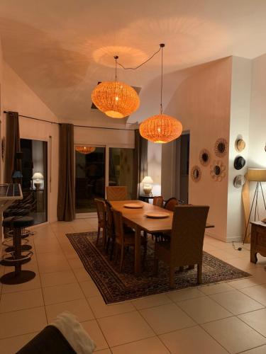 a dining room with a table and chairs and lights at La petite duchesse - jaccuzzi in Plérin
