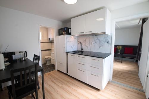 a kitchen with white cabinets and a black counter top at Lake Getaway Apartment with Private entrance, right on the Lake Constance cycle path, barbecue area, free wifi, Netflix and free bikes in Salmsach