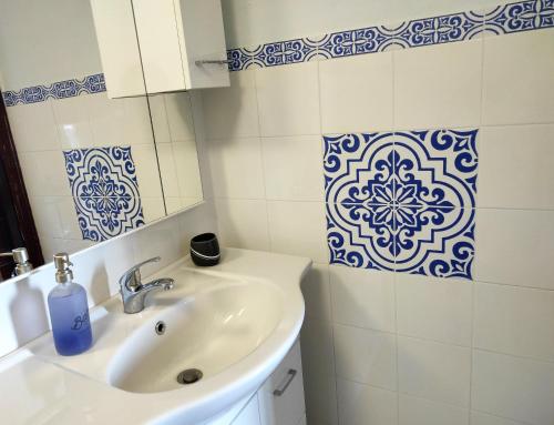 baño con lavabo y azulejos azules y blancos en Aeolian Sea House, en Santa Marina Salina