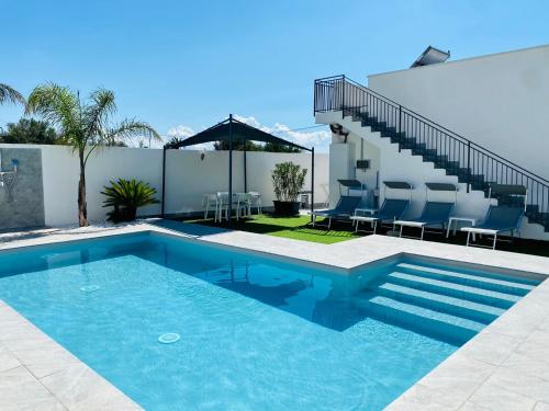 a swimming pool with blue chairs and a house at Katy's Holiday House, Private Villa in Terrasini