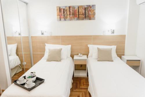 two beds in a room with white sheets at Mediterráneo Hotel y Spa in Rosario