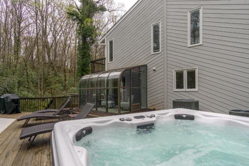 a hot tub on a deck next to a house at Secluded oasis in Asheville! GAME room MOVIE theater HOT tub - 20 min to Biltmore! in Fairview