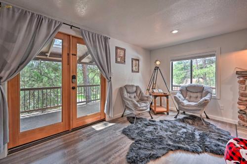 a living room with two chairs and a table and windows at Hot Tub, Game Room Dog-Friendly Pine Cabin! in Pine
