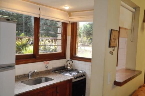 a kitchen with a sink and a stove and a window at Calamoresca Complejo de Cabanas in Mar de las Pampas