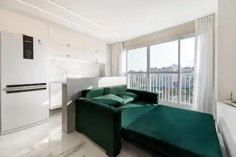 a living room with a green couch in front of a window at Suite Verano Stay in Rio de Janeiro