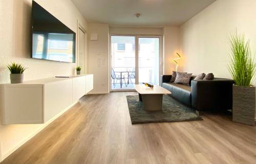 uma sala de estar com um sofá e uma mesa em Auszeit Apartment STYLE am Uferpark - nur 100 m bis zum Bodensee, direkt am Bodenseeradweg, Sonnenbalkon, schnelles WLAN, kostenloser Tiefgaragenstellplatz, für bis zu 2 Personen em Friedrichshafen