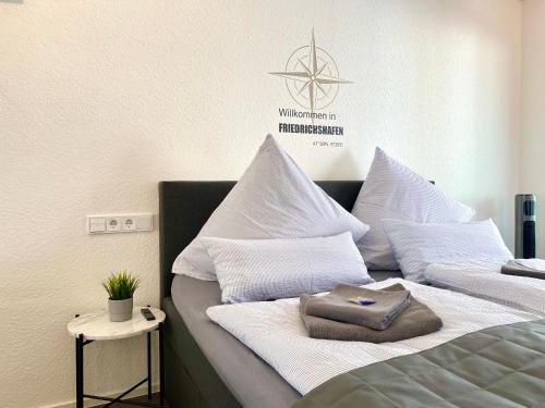 ein Bett mit weißen Kissen drauf mit in der Unterkunft Auszeit Apartment STYLE am Uferpark - nur 100 m bis zum Bodensee, direkt am Bodenseeradweg, Sonnenbalkon, schnelles WLAN, kostenloser Tiefgaragenstellplatz, für bis zu 2 Personen in Friedrichshafen