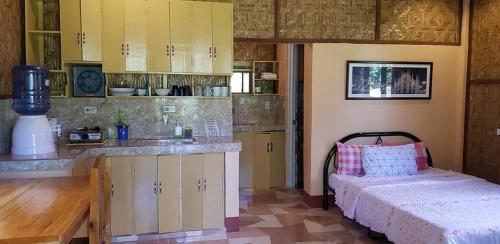 una cocina con armarios amarillos y una cama en una habitación en Paco's Garden Home Stay, en Mambajao