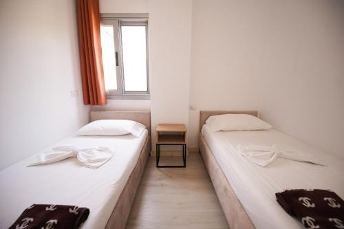 two beds in a small room with a window at Vila Milo in Himare