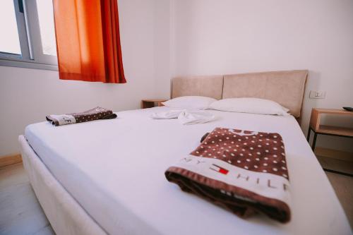 a white bed with two towels on top of it at Vila Milo in Himare