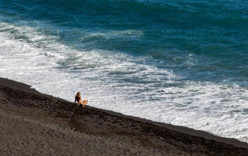 カンデラリアにあるTHE HAPPINESS PENTHOUSE Dream Holiday at 100m Beach!の海を眺めながら海辺に座る女