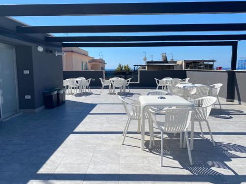 un patio con mesas blancas y sillas en la azotea en IL VIAGGIATORE RELAIS SUL MARE, en Gaeta
