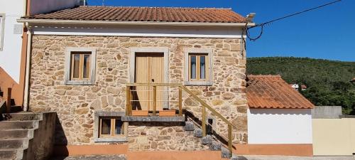 a stone house with a wooden door and a balcony at Casa Pregueira in Lisboinha