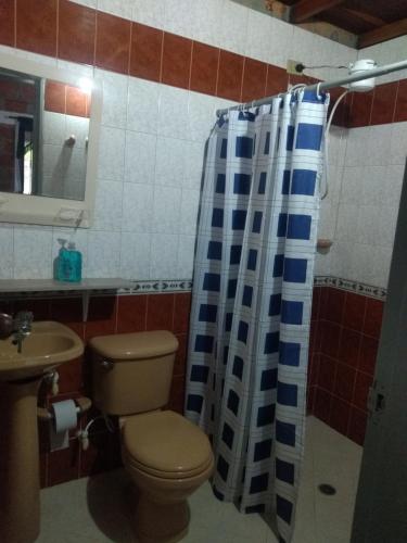 y baño con aseo y cortina de ducha. en Akasha Encuentro Finca cerca a Medellín., en Guarne