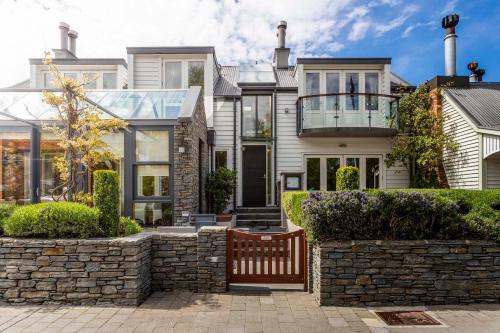 a house with a stone wall and a balcony at Eichardt's Private Hotel in Queenstown