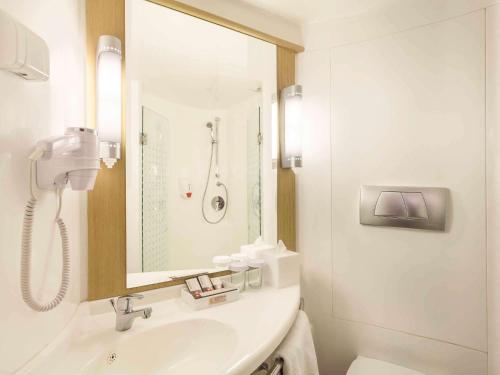 a white bathroom with a sink and a shower at Ibis Balikpapan in Balikpapan