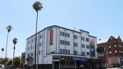 a white building on a city street with palm trees at Hometel Suites in Los Angeles