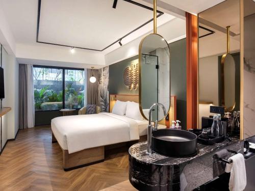 a bedroom with a bed and a sink and a mirror at Tribe Bali Kuta Beach in Kuta