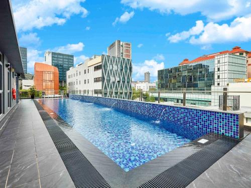 a large blue pool in the middle of a city at Ibis Budget Singapore Clarke Quay in Singapore