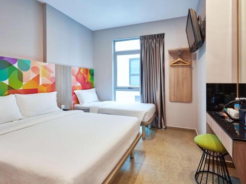 een hotelkamer met 2 bedden en een televisie bij ibis budget Singapore Clarke Quay in Singapore