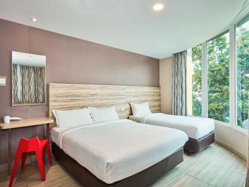 a hotel room with two beds and a red stool at ibis budget Singapore Crystal in Singapore