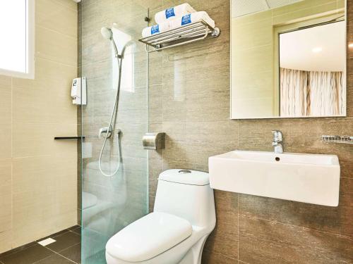 La salle de bains est pourvue de toilettes, d'un lavabo et d'une douche. dans l'établissement ibis budget Singapore Crystal, à Singapour