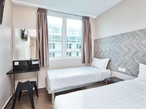 ein Hotelzimmer mit zwei Betten und einem Fenster in der Unterkunft ibis budget Singapore Ruby in Singapur