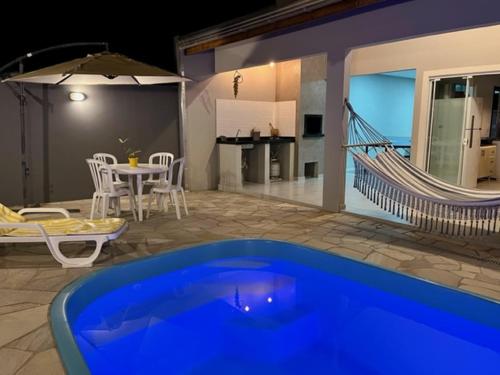 a swimming pool with a hammock and a house at Casa Sol com piscina in Balneario Barra do Sul