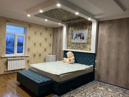 a teddy bear sitting on a bed in a bedroom at Green house in Nukus