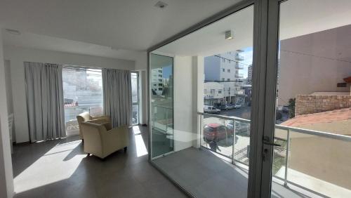 a living room with glass doors and a chair at Amanecerpuertomadryn 1 in Puerto Madryn