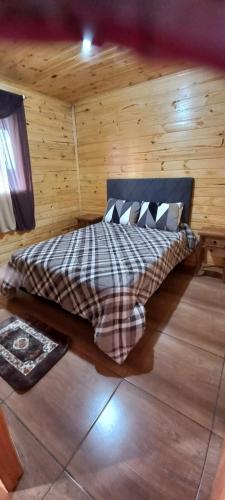 Un dormitorio con una cama en una cabaña de troncos en Cabanas Campinho, en Mundo Novo